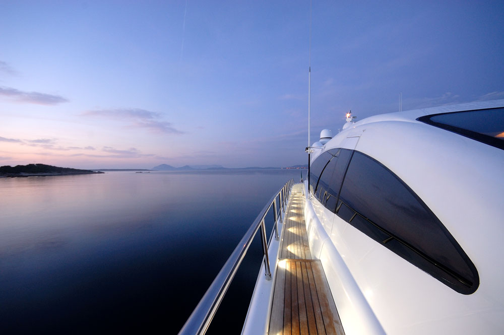 Vista prospettica del corridoio sinistro e finestratura dello yacht Mangusta 108' ARES verso prua all'alba, con giochi di luce e riflessi